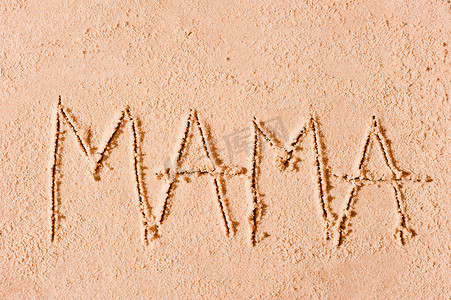沙滩上的孩子摄影照片_孩子在沙滩上的沙子上写下妈妈这个词