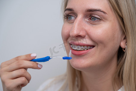 白种女人用刷子清洁她戴着牙套的牙齿。
