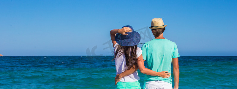 热带度假期间在白色沙滩上浪漫情侣的背影
