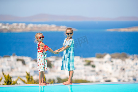 暑假游泳摄影照片_可爱的小女孩在希腊暑假时在室外游泳池边