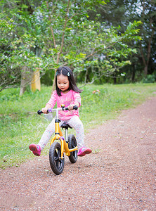 斜坡自行车摄影照片_小女孩在公园的斜坡上学骑平衡车