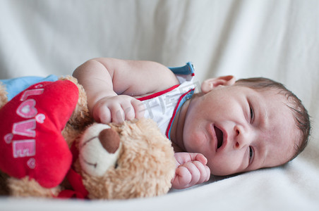 哭泣摄影照片_哭泣的小婴儿与玩具熊的肖像