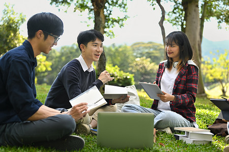 在美好的一天，一群友好的大学生在课后坐在公园里互相交谈