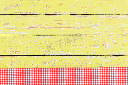 黄色木桌面背景纹理，带有质朴的红色桌布