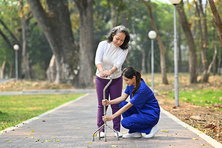 细心的女性护理人员帮助、教高级女性与助行器一起走路。