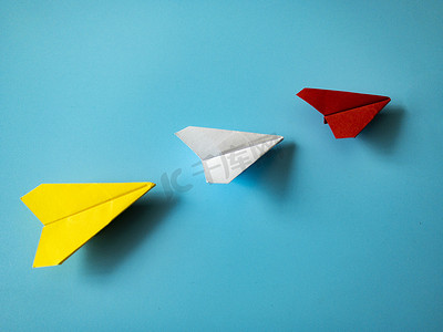 红色纸飞机折纸在蓝色背景上领先白色和黄色飞机，带有可定制的文本空间。