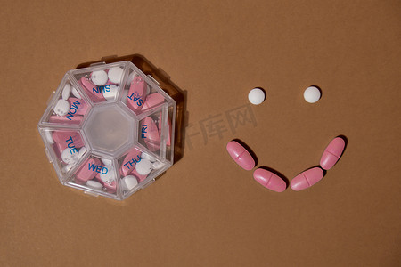 健康用药摄影照片_组织者每周用药片微笑拍摄，每天服用白色粉红色药物和胶囊。
