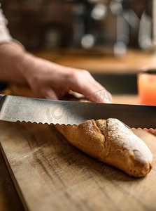 剪刀手icon摄影照片_女孩用刀手切法式长棍面包