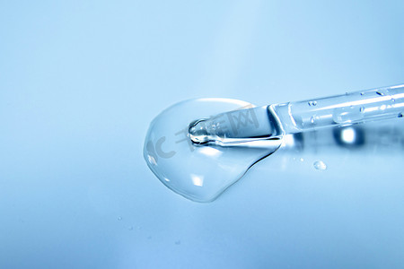 透明水泡摄影照片_在实验室玻璃移液器的蓝色背景上，带有化妆品液滴的水泡。