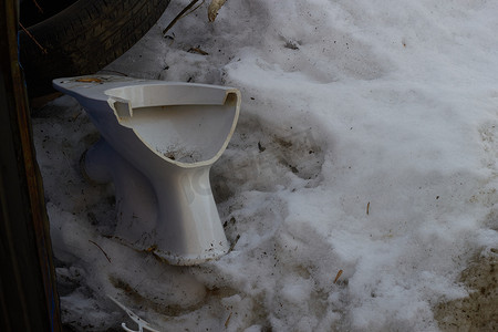 破碎马桶摄影照片_破碎的白色马桶背景脏雪。