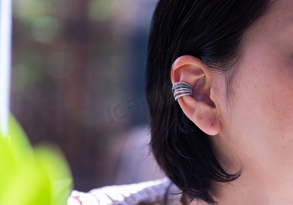 银耳环摄影照片_戴漂亮银耳环的年轻女子的细节。