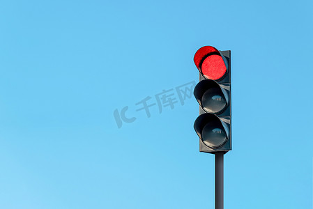 有红灯的现代红绿灯在无云的晴朗的蓝天前面