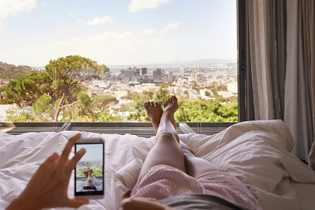 床、电话和带脚的窗景，放松和摄影，用于博客、评论和酒店屏幕。