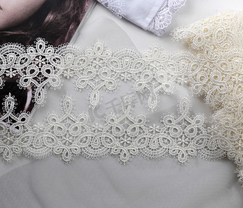 本色白色凸花带，浅色背景上的美丽丝绸蕾丝面料。