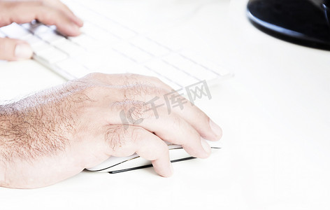 男性手点击白色鼠标，右侧有白色键盘。