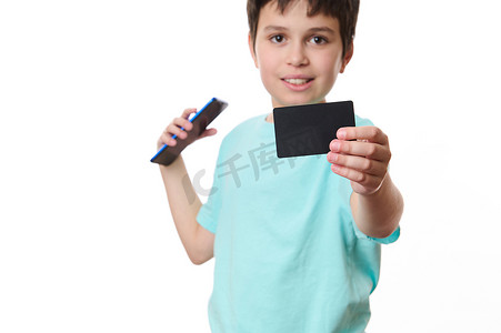 移动电子支付摄影照片_专注于白色背景中孤立的模糊少年手中带有空白促销文本的黑色信用卡