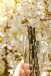 自然背景中可重复使用的玻璃吸管，绿叶春花环保。
