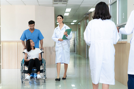 运送病人摄影照片_医生和护士在无菌走廊用轮椅运送女病人。