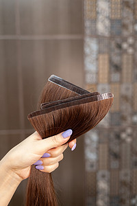 发夹发带矢量图摄影照片_一个女人手里拿着发带在家里接发。