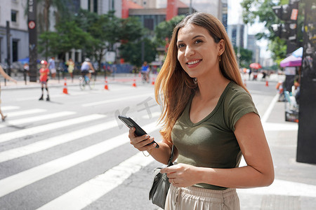 巴西圣保罗保利斯塔大街上使用智能手机的巴西女性望向远方