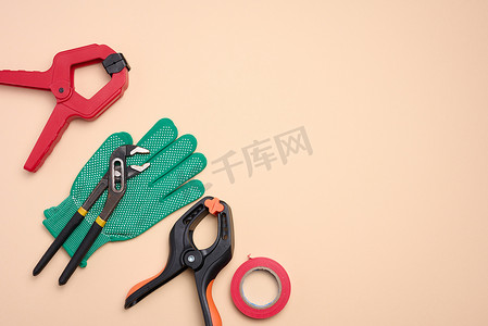 米色背景上的绿色手套和金属通用可调扳手，顶视图