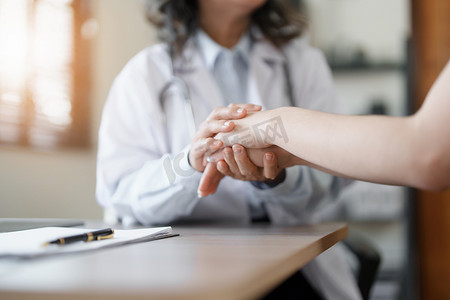 一位女医生握着病人的手鼓励与疾病作斗争的画像。