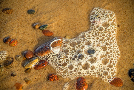与海浪和小卵石泡沫的沙滩