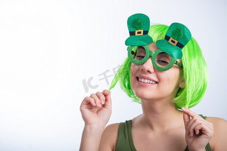 戴着绿色假发和滑稽眼镜的快乐的年轻女子在白色背景上庆祝圣帕特里克节。