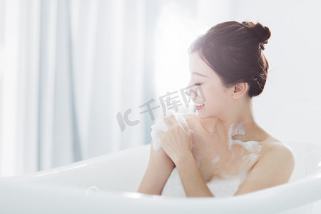 浴缸摄影照片_年轻女子在浴缸里洗澡