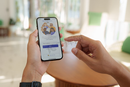 泰国清迈 - 2023 年 2 月 12 日：一名在家工作的男子使用 iphone 14 的 Microsoft Teams 应用程序。