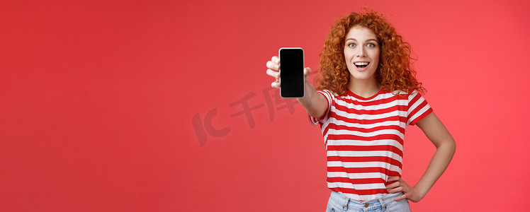 手机app页面摄影照片_欢快迷人的魅力欧洲红发女孩卷发秀智能手机屏幕快乐地微笑推广应用程序建议推荐良好的应用程序社交媒体页面红色背景
