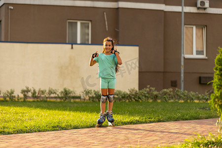 溜旱冰摄影照片_在城市街道上溜旱冰的可爱快乐小女孩