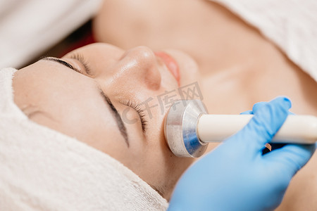 在美容院 spa 中使用超声波按摩设备进行面部提升激活胶原蛋白和紧肤的特写人。