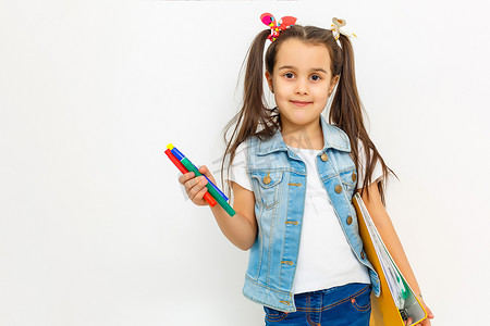 快乐甜美的小女孩背着书包背包和书在教育中微笑，回到学校概念孤立在白色背景中