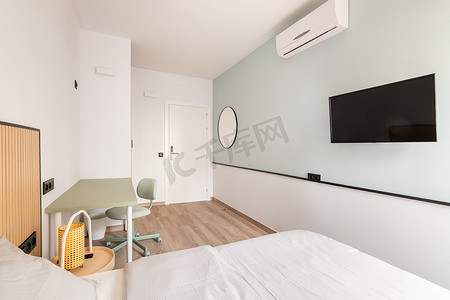 空荡荡的明亮房间，配有床、书桌、书桌、空调和浅绿色和白色墙壁背景的电视。