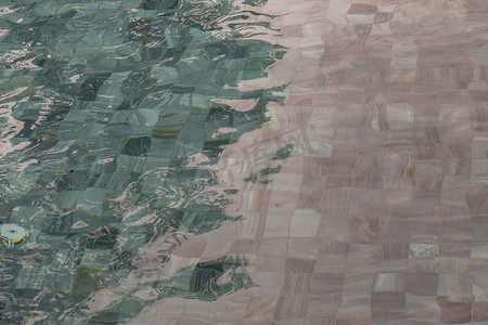太阳反射在游泳池蓝色清澈的水波纹上。