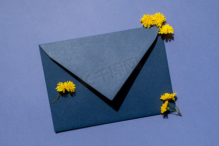 美丽的黄色小洋甘菊雏菊花在紫色背景的邮政蓝色信封上，空白的纸条复制空间用于文本，春天，假期贺卡。