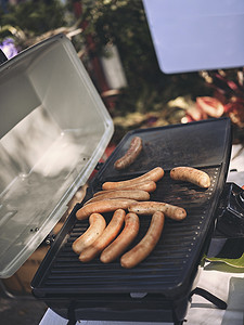 热狗肠摄影照片_户外烧烤的新鲜香肠和热狗。
