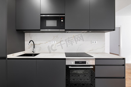简约格调摄影照片_带灰色木炭面板和白色大理石条的现代简约厨房。