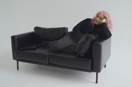 假发摄影照片_沙发上睡着一个戴着粉色假发的男人。