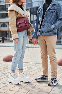 一对穿着休闲保暖衣服的快乐夫妇在商业大楼附近的城市户外散步
