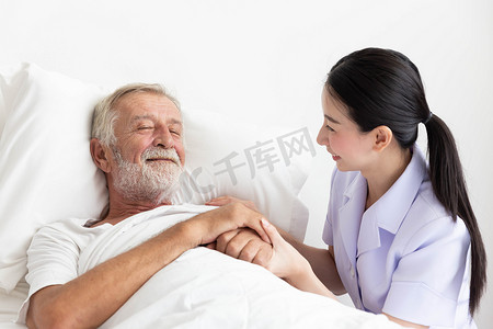 躺在床上摄影照片_护士照顾躺在床上的老人