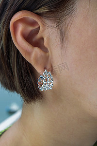 戴漂亮银耳环的年轻女子的细节。