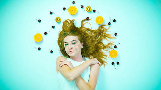 女孩的顶部视图有水果、头发附近的樱桃、猕猴桃和橙子以及一个女孩。特写镜头。
