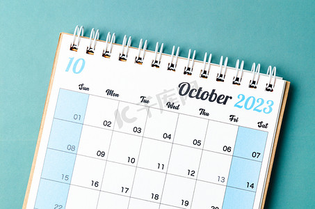 年度计划摄影照片_一张 2023 年 10 月的日历桌，供组织者在蓝色背景下进行计划和提醒。