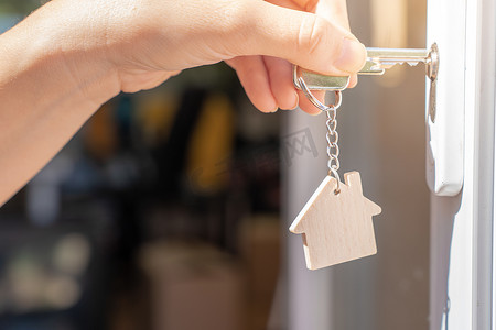 用钥匙和家居形状的钥匙扣打开通往新家的门。