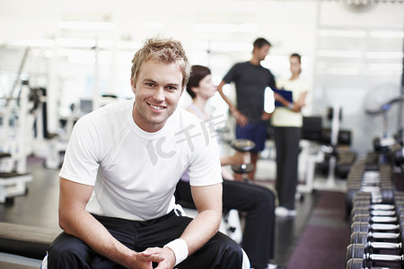 You gotta put the work in. 一个英俊的年轻人坐在健身房里。