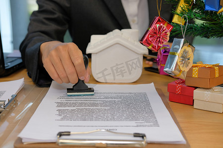 批准盖章摄影照片_房地产经纪人在圣诞节期间在抵押贷款合同协议文件上盖章