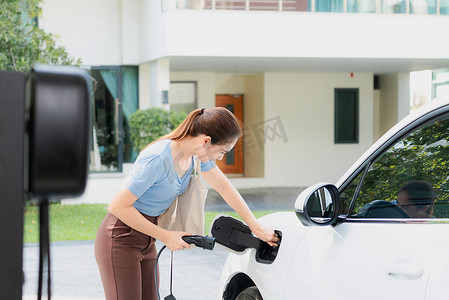 进步女性在家里的充电站给她的 EV 汽车充电。