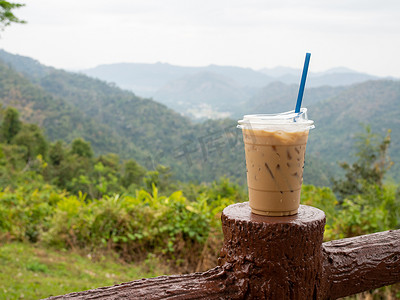 在群山和天空的映衬下，围栏上放着一杯冰咖啡。